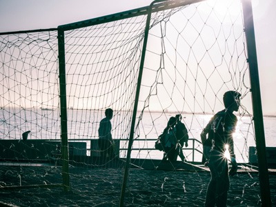 Kids playing football during a sunset